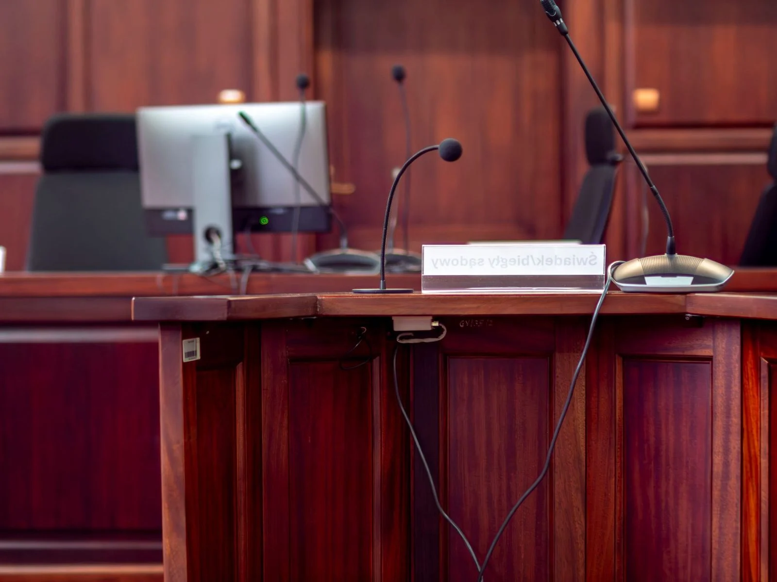 Podio de madera con micrófono en sala de audiencias judicial.