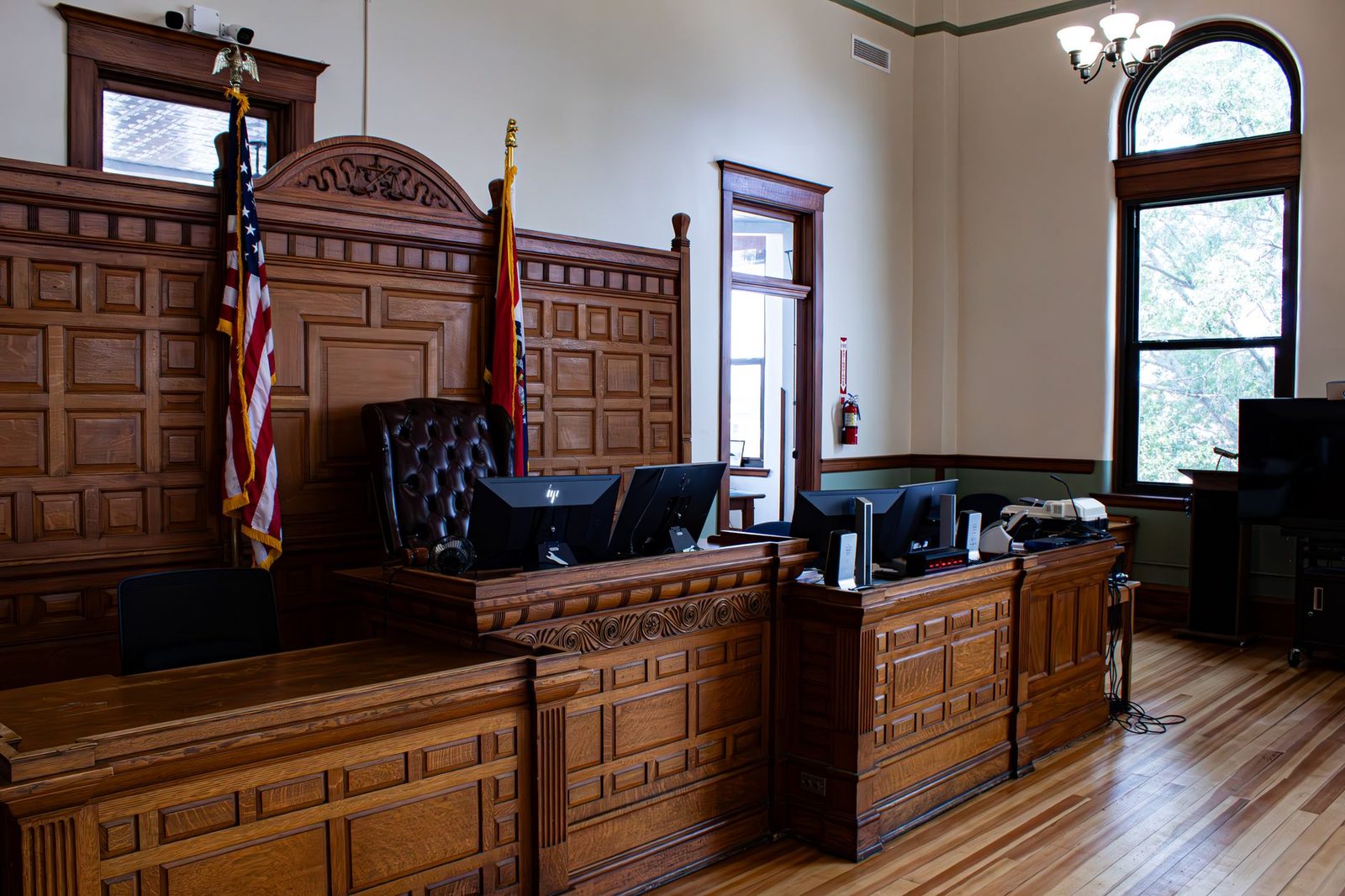 Sala de tribunal estadounidense con escritorio del juez y banderas.