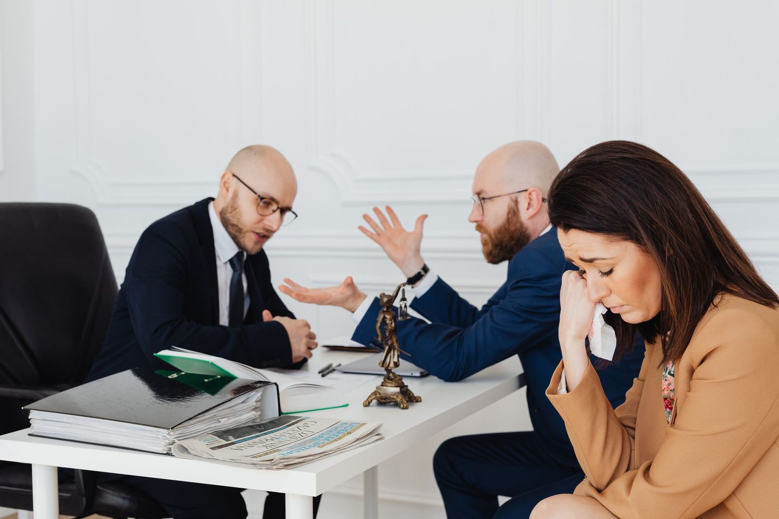 Woman looking distressed while two lawyers discuss in an office.