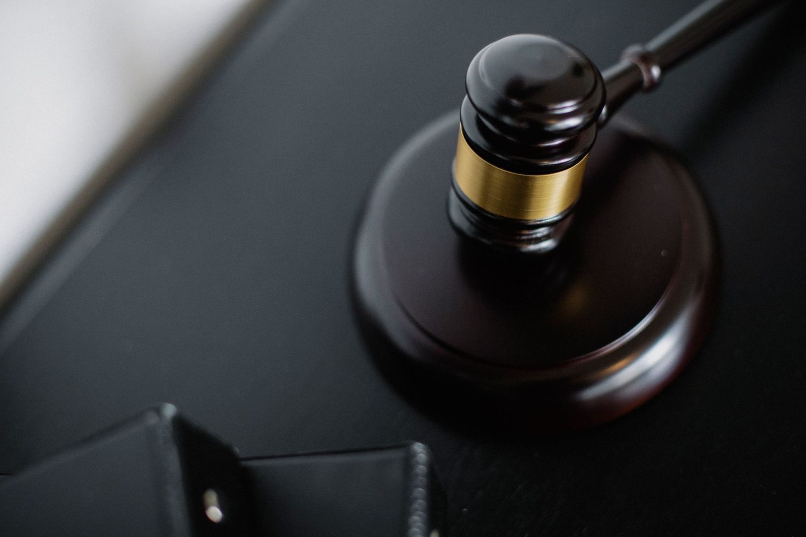 Wooden gavel on round surface with folders on courtroom table, overhead view.