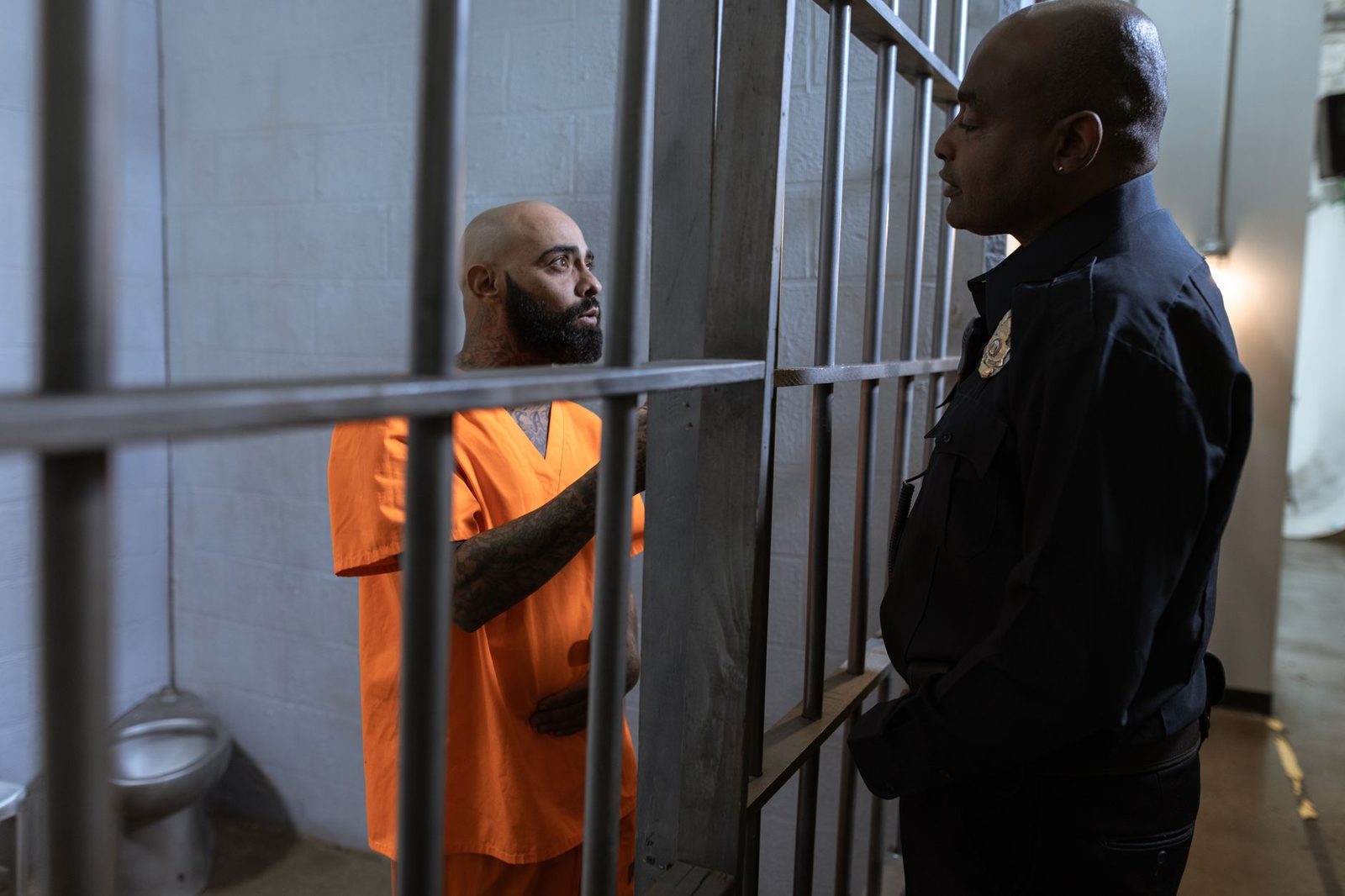 A correctional officer speaks with an inmate inside a prison cell.