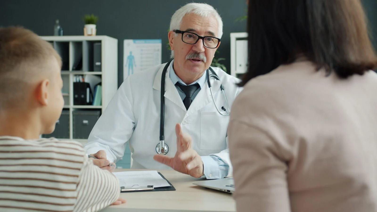 Un médico se reúne con una familia en una oficina clínica luminosa para hablar de opciones de tratamiento.