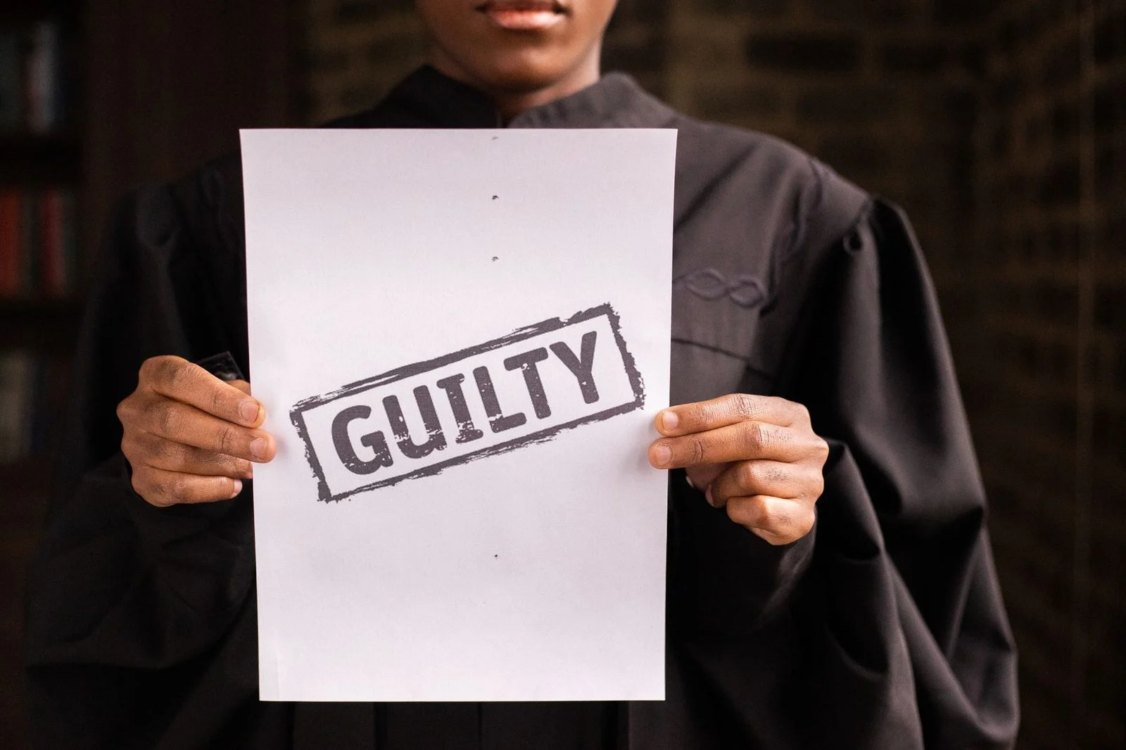 A judge in a courtroom holding a paper, with a gavel and wooden bench in the background.