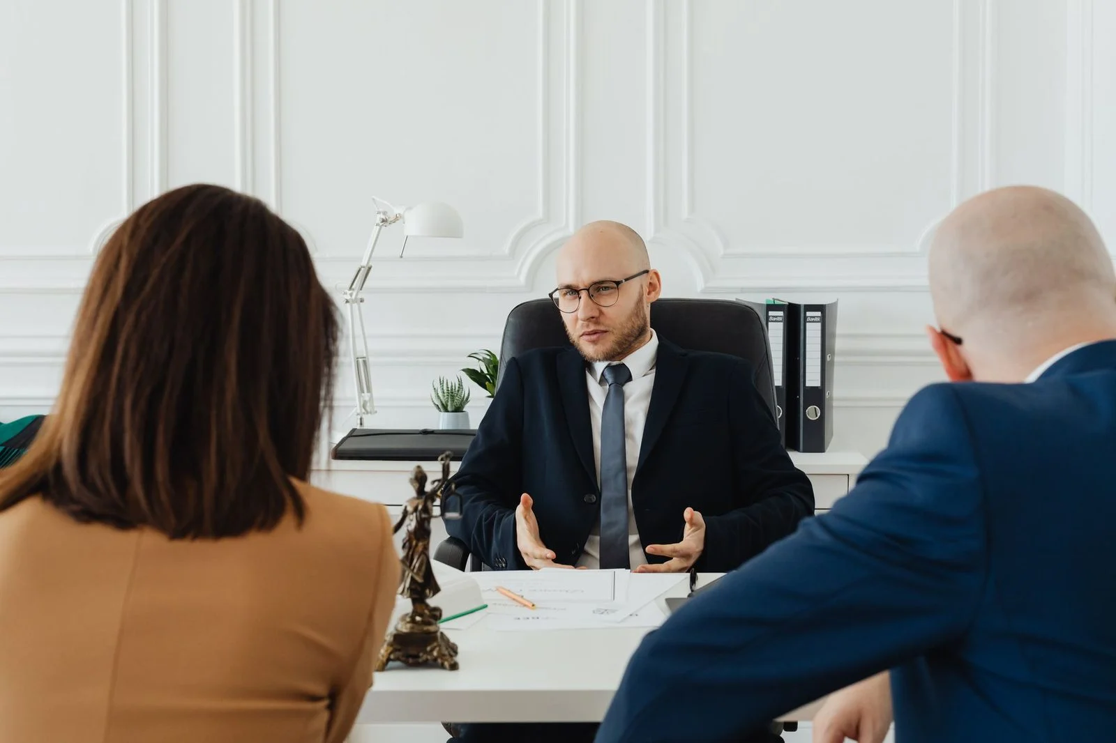 Abogado y clientes reunidos en una mesa de una oficina moderna.