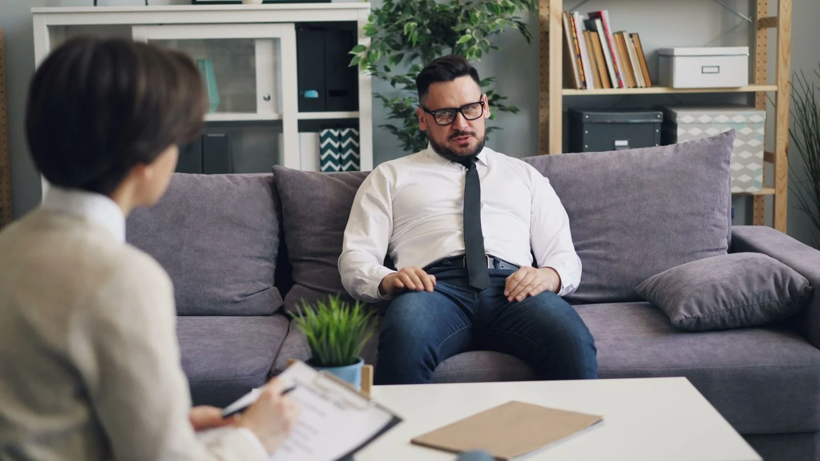 A man sits across from a psychologist in a cozy office during a therapy session.