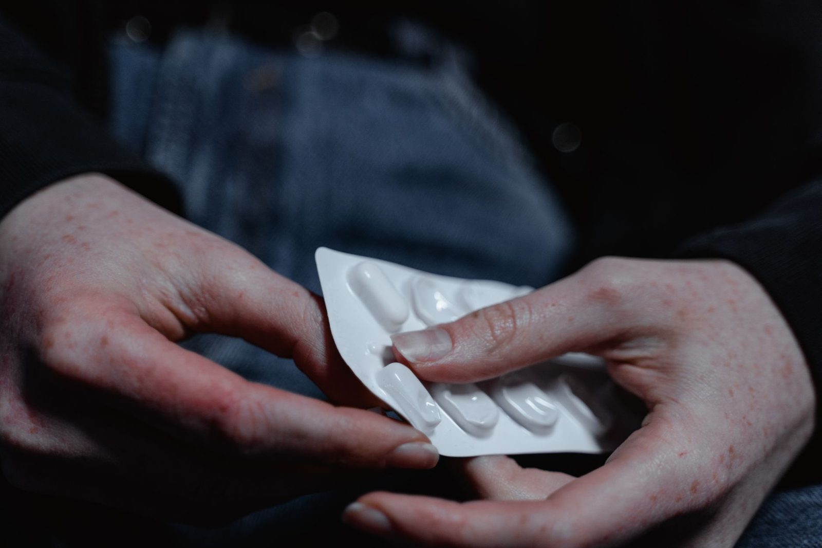 A person's hands hold a blister pack of pills, suggesting health and treatment themes.