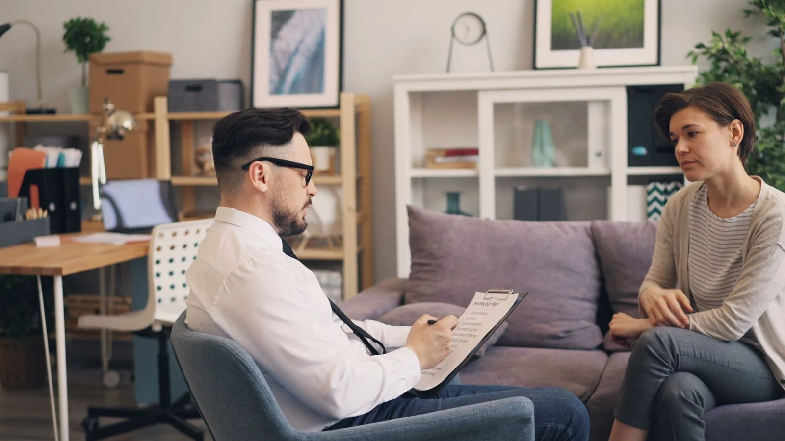 A therapist and a female patient talk together during a consultation in a cozy office.