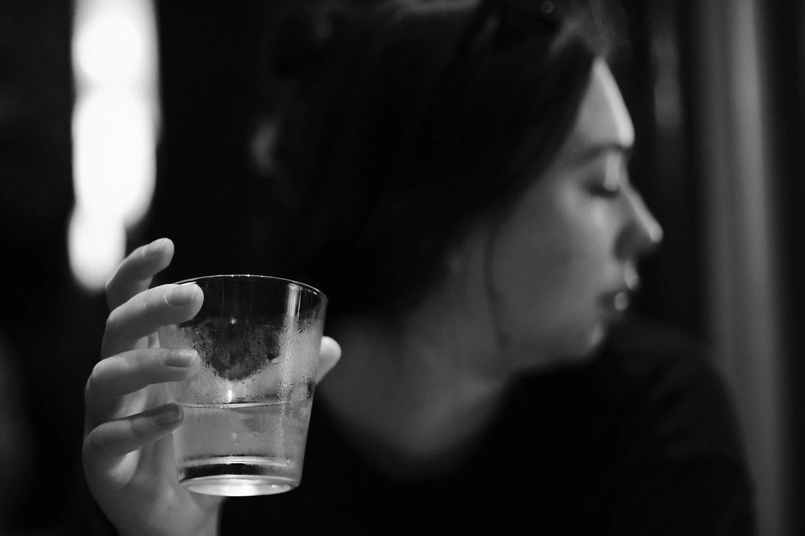 Black and white close-up of a woman's hand holding a glass of drink.