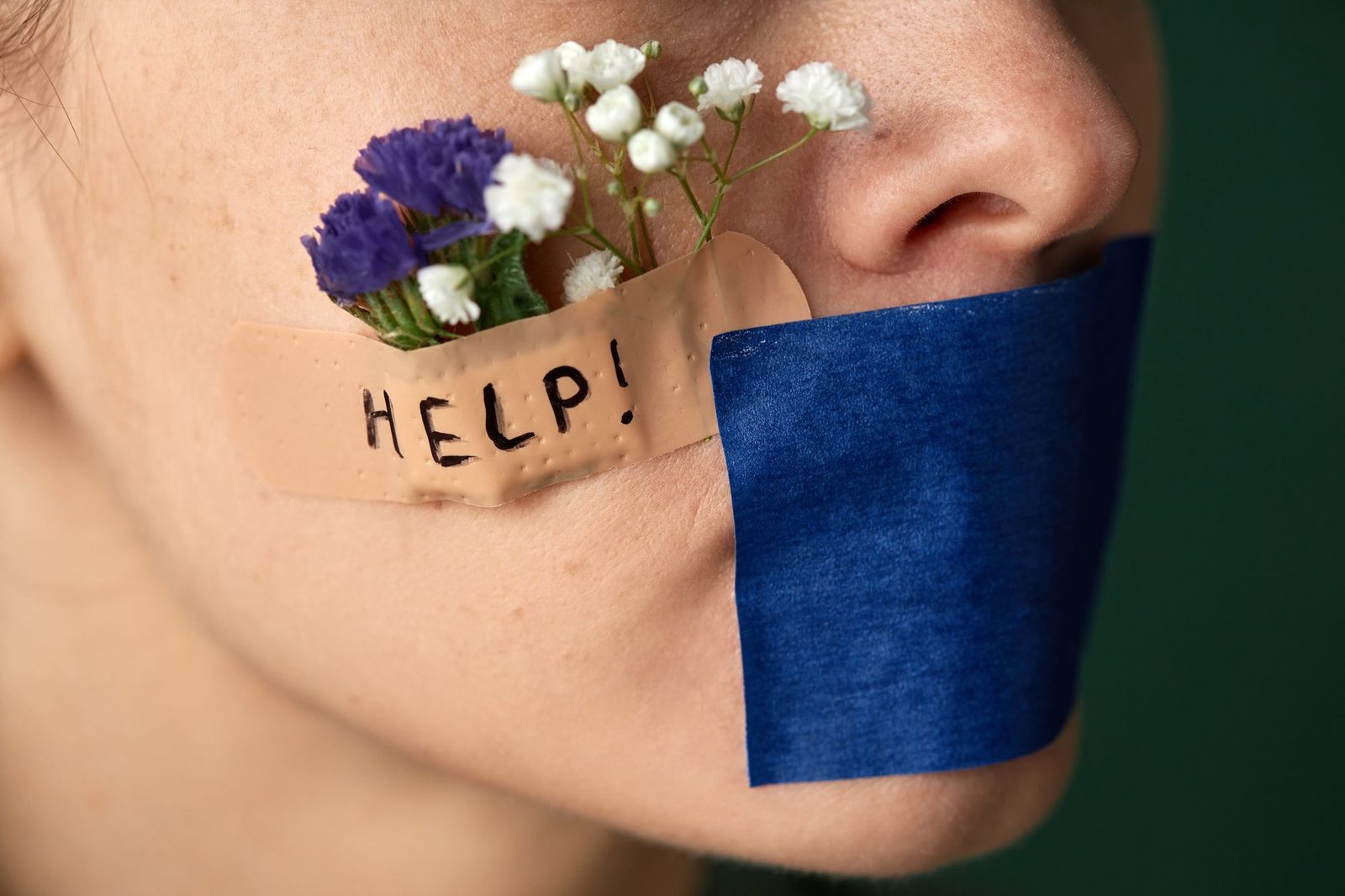 Primer plano de un rostro con flores y cinta adhesiva cubriendo la boca.