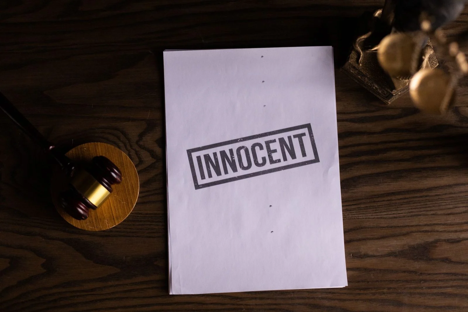 Legal document stamped "Innocent" beside a gavel on a wooden desk.