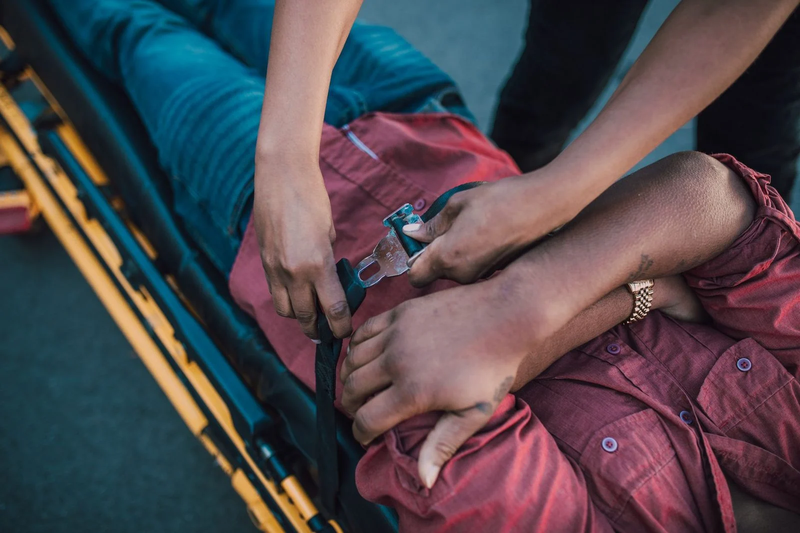 Close-up of a person securing an injured individual onto a stretcher for emergency care.