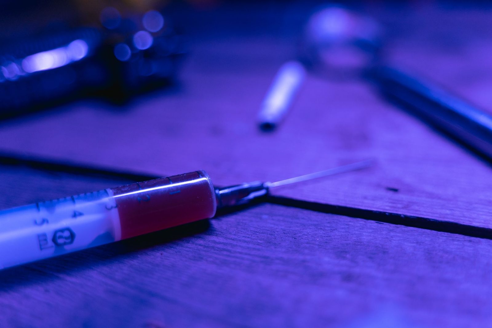 Close-up of a syringe in dim, moody lighting, representing the dangers of addiction and the need for treatment.