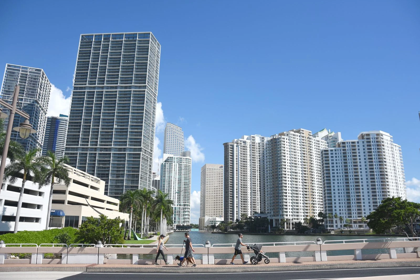Rascacielos del centro de Miami bajo un cielo azul despejado, con peatones cruzando un puente.