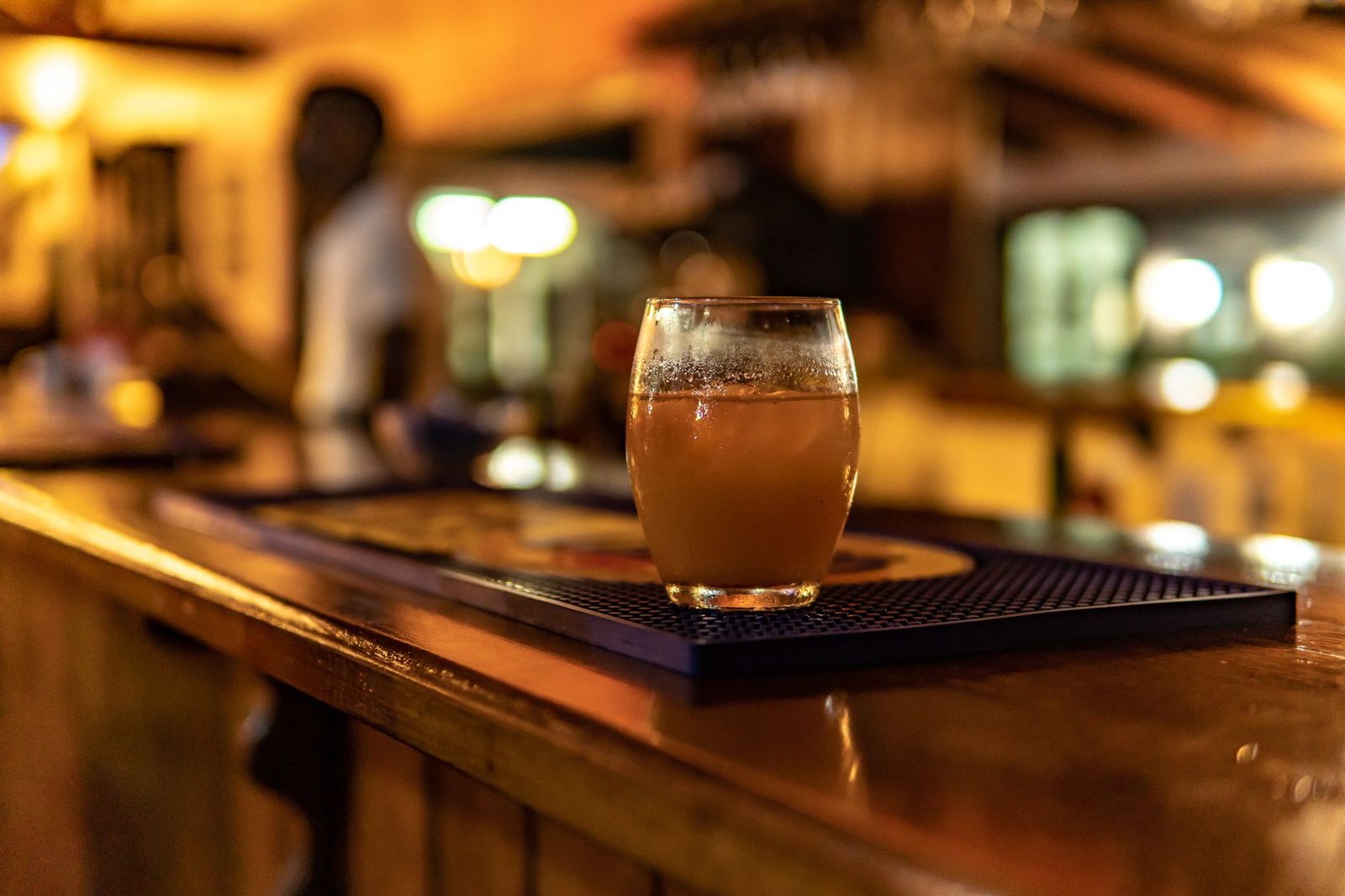 Glass of alcohol on a bar counter with blurred background.