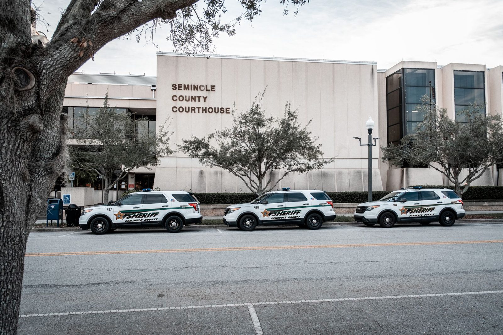 Law enforcement vehicles parked outside a courthouse building.