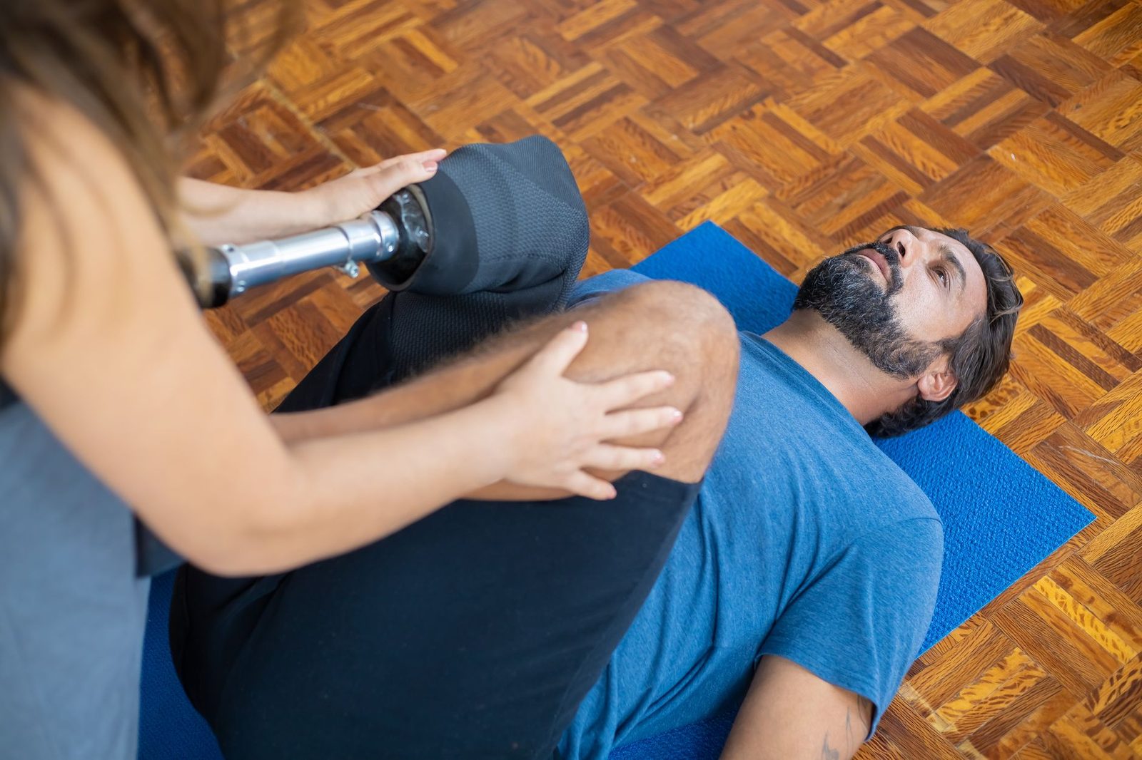 Man with a prosthetic leg receives physical therapy indoors during rehabilitation.