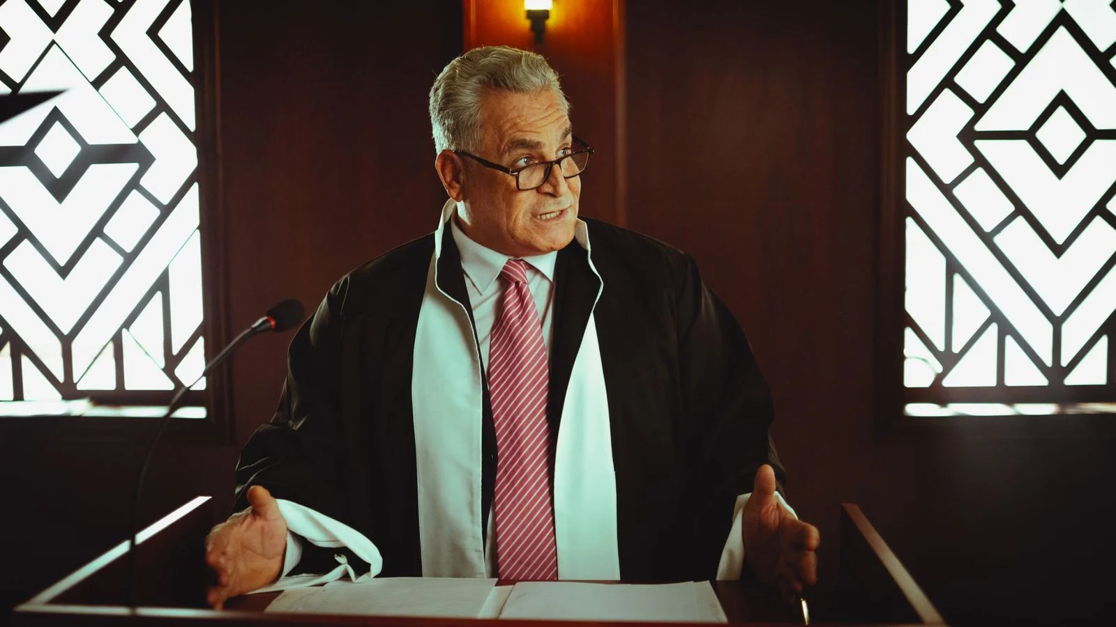 Senior male lawyer presenting a case in a Baghdad courtroom, wearing a classic black robe.