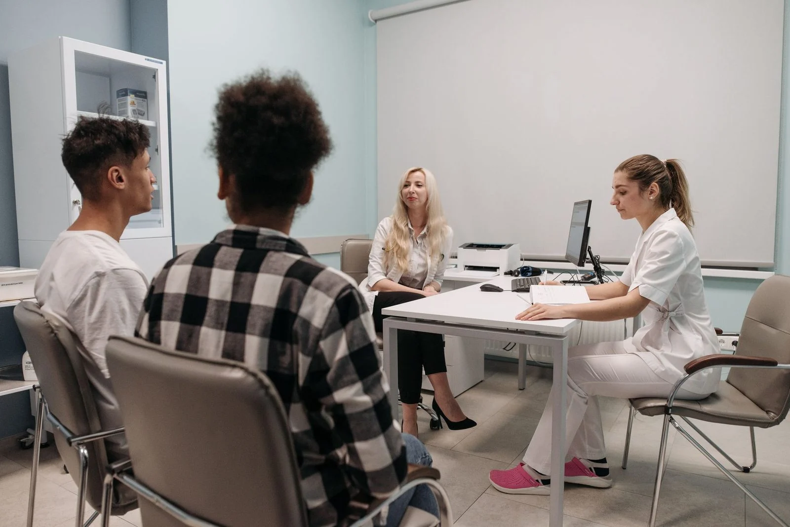 Dos médicos conversan con un paciente en un consultorio luminoso.