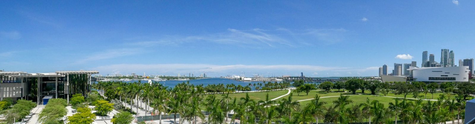 Vista del horizonte de Miami sobre parques verdes bajo un cielo azul despejado.
