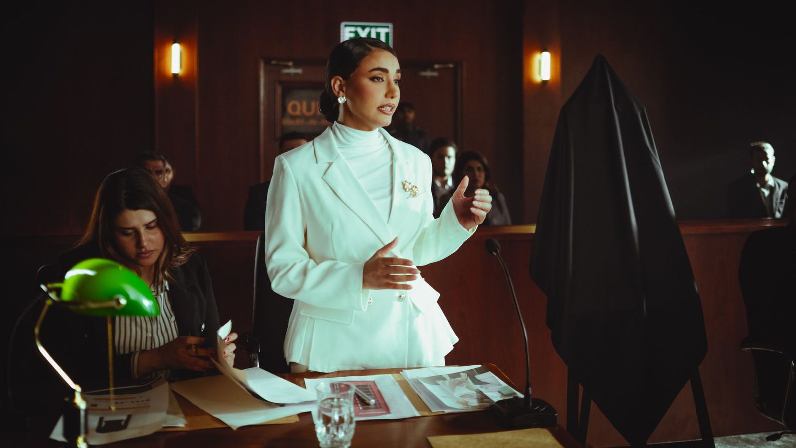Woman in white suit presenting legal case in courtroom.