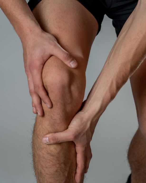 man touching injured knee