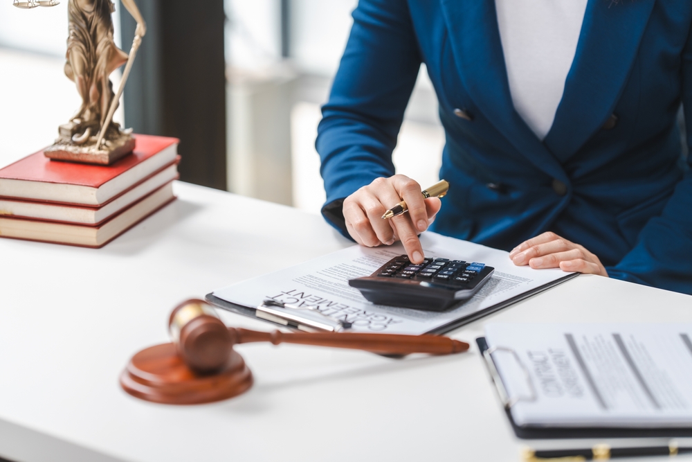 Lawyer calculating Marchman Act expenses, with a legal contract, gavel, and law books on the table